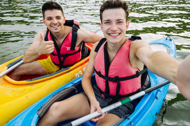 Male friends taking self portrait while kayaking