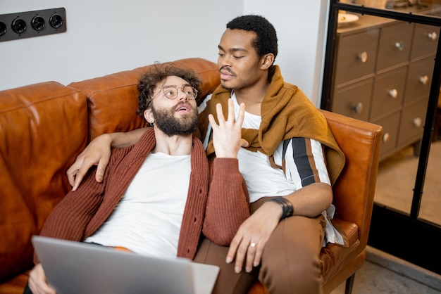 Male gay couple talking on a couch at home