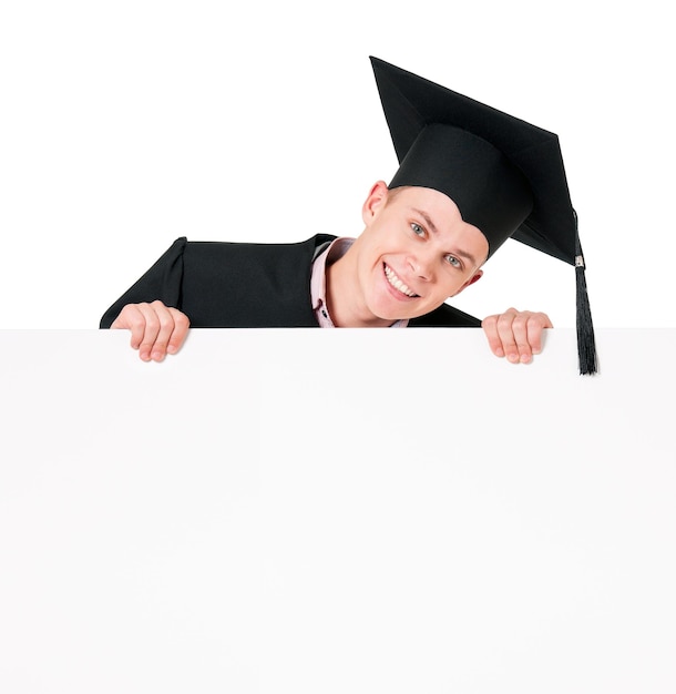 Male graduate student peeking from behind a blank panel isolated on white background