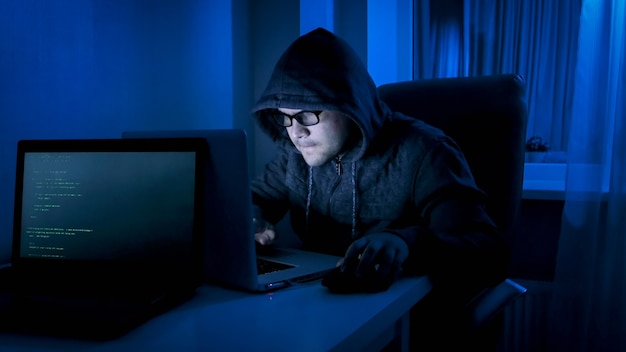 Male hacker working on laptop from home at night