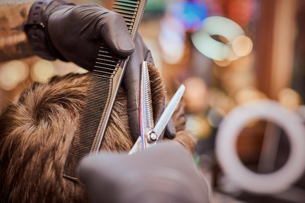 Male haircut in barbershop close up client getting haircut by hairdresser with comb and scissors