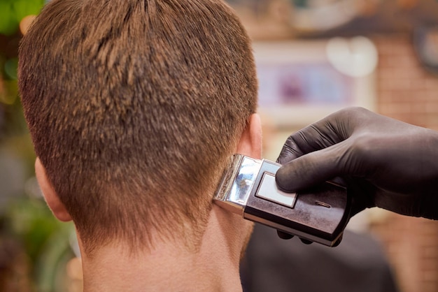 Male haircut shaving in barbershop client getting haircut by hairdresser with electric shaver