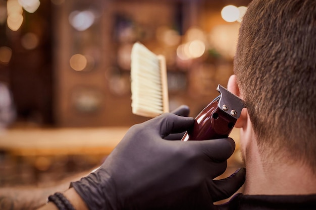 Male haircut trimming in barbershop client getting haircut by hairdresser with clipper hairbrush