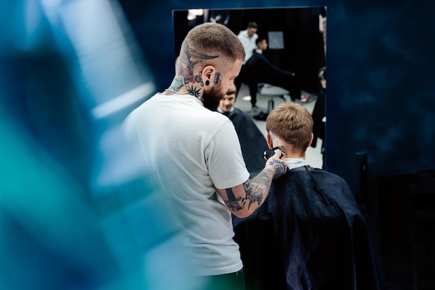 Male haircut with electric razor Tattooed Barber makes haircut for client at the barber shop by using hairclipper Man hairdressing with electric shaver