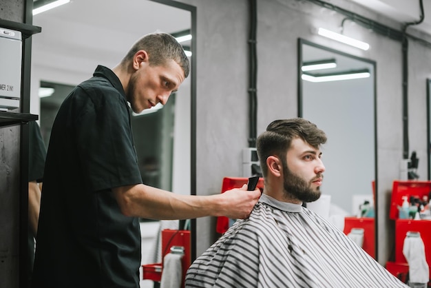 Male hairdresser doing stylish hairstyle to bearded man