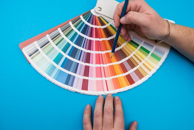 Male hand choosing paint tone at color sampler isolated