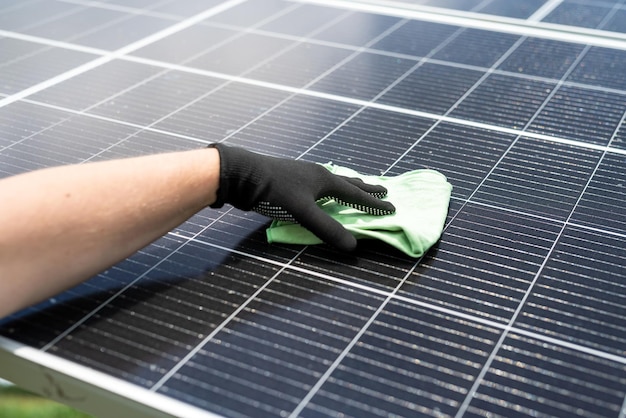 Male hand cleaning solar panels with towel to wipe dirty Solar power for green energy