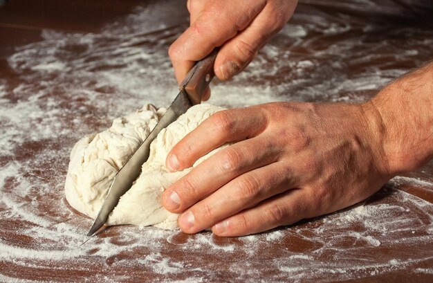 Male hand cut the dough for baking