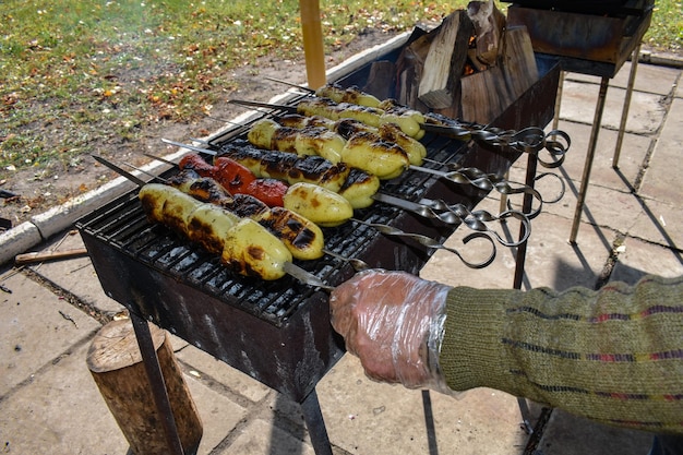 Male hand flips a skewer with grilled pepper