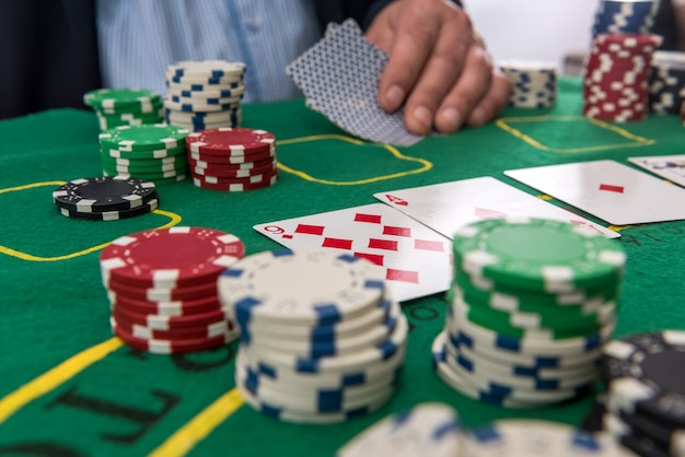 Male hand hold  chips and cards for poker on casino table. Gaming business, success concept