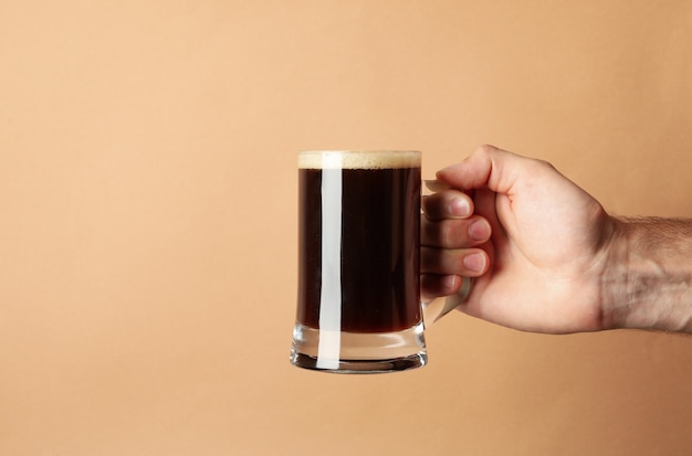 Male hand hold glass of beer on brown background