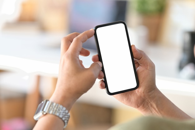 Male hand holding blank screen mobile phone in office.