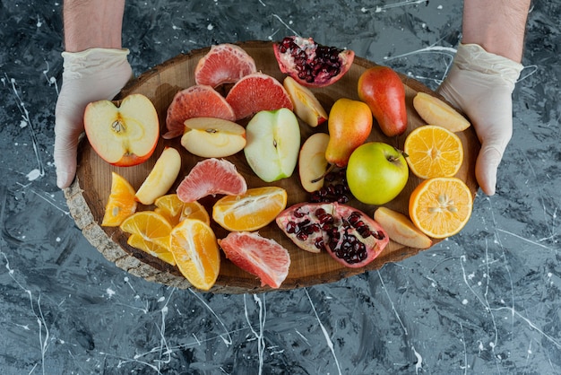 Male hand holding bunch of fresh fruits on marble table.