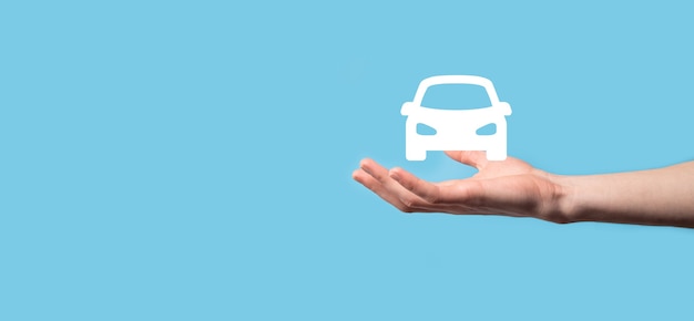 Male hand holding car auto icon on blue background. Wide banner composition.