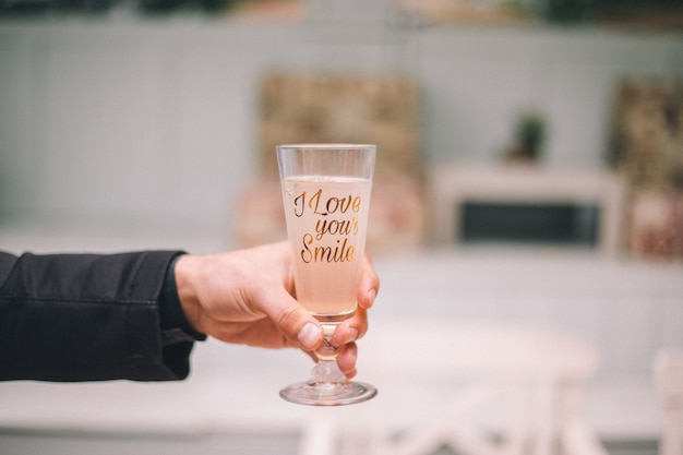 Male hand holding a glass with a drink. The inscription on the glass:  I love your smile