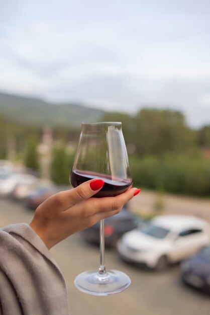 Male hand holding glass with wine on blurred natural background.