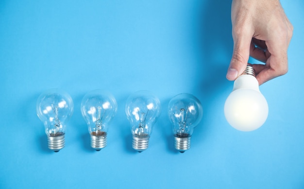 Male hand holding light bulb on blue