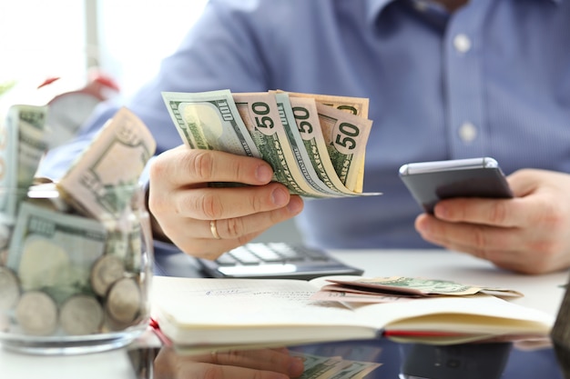 Male hand holding pack of banknotes and cellphone