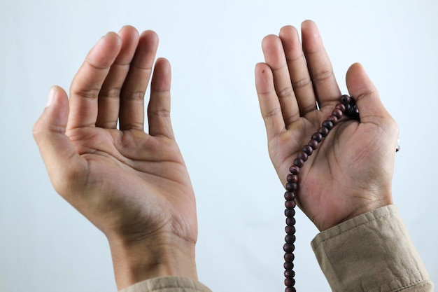 Male hand holding prayer beads rosary on white background Ramadan kareem and ied mubarak concept