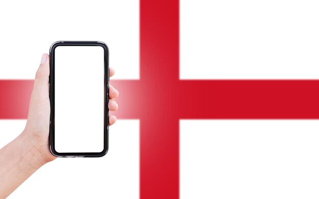 Male hand holding smartphone with blank on screen on background of blurred flag of England Closeup view