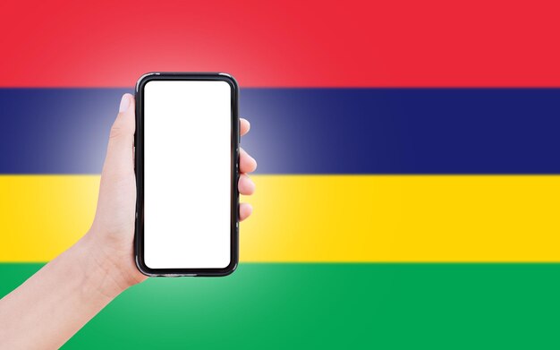 Male hand holding smartphone with blank on screen on background of blurred flag of Mauritius Closeup view