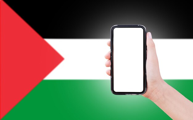 Male hand holding smartphone with blank on screen on background of blurred flag of Palestine Closeup view