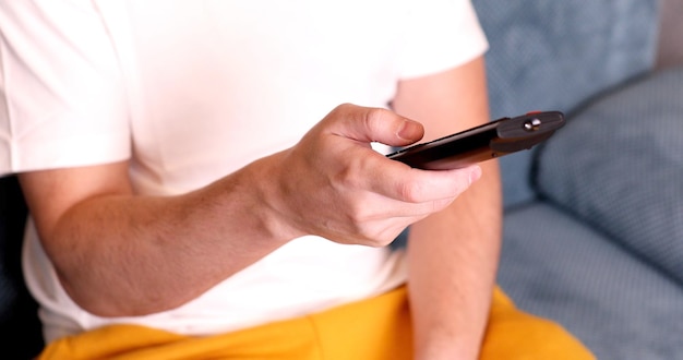 Male hand holding TV remote control.