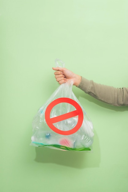 Male hand holding a waste bag isolated on green background