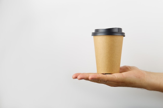 Male hand holds on his palm a take away coffee paper cup isolated on white background