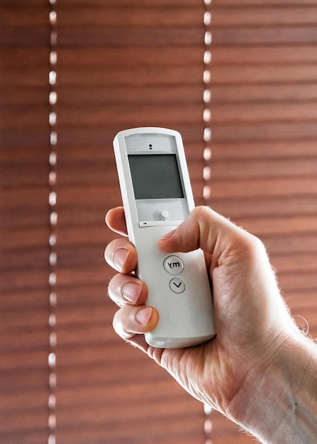 male hand holds a remote control to open the window blinds