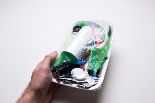 Male hand holds a tray with plastic waste