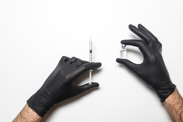 Male hand in a medical glove with a vaccine on a white surface