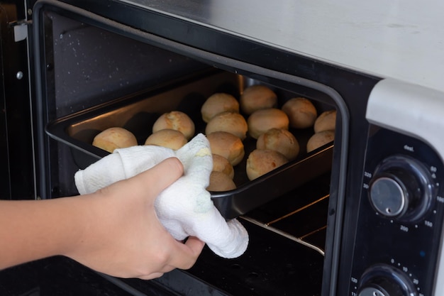 male hand picking up baked cheese buns on a stove. homemade brazilian pao de queijo snack