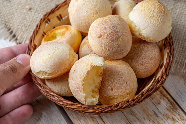 Male hand picking up basket with cheese breads traditional brazilian breakfast concept