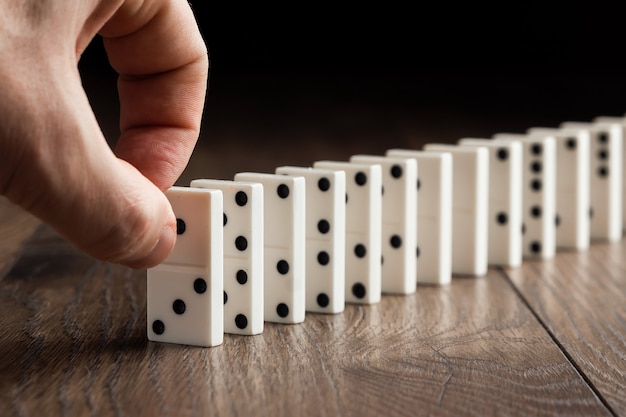 Male hand pushing white dominoes