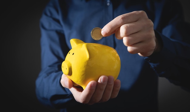 Male hand putting coin to piggy bank Saving