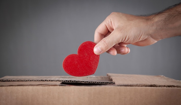 Male hand putting red heart in box