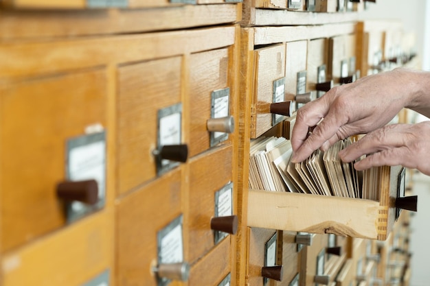 A male hand searching cards in old card catalogue Man searching file