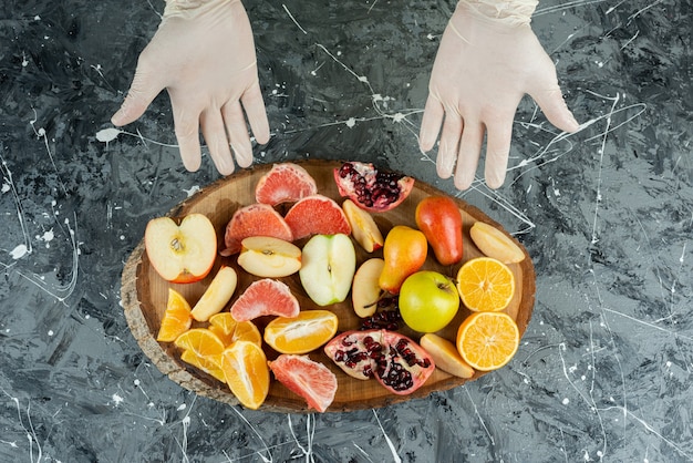 Male hand showing bunch of fresh fruits on marble table.