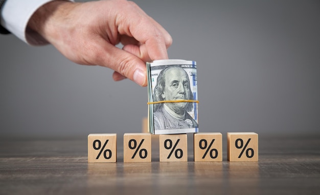 Male hand showing dollar and percent symbols on wooden cubes