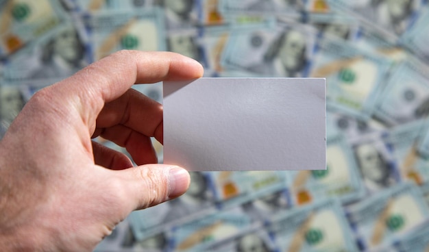 Male hand showing empty business card on dollar banknote background