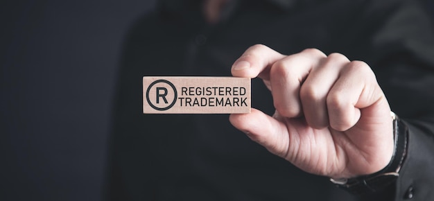 Male hand showing RRegistered trademark on wooden block