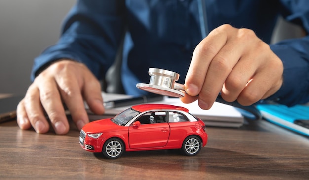 Male hand showing stethoscope over car model