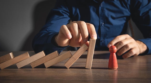 Male hand stopping wooden blocks from falling on human figure