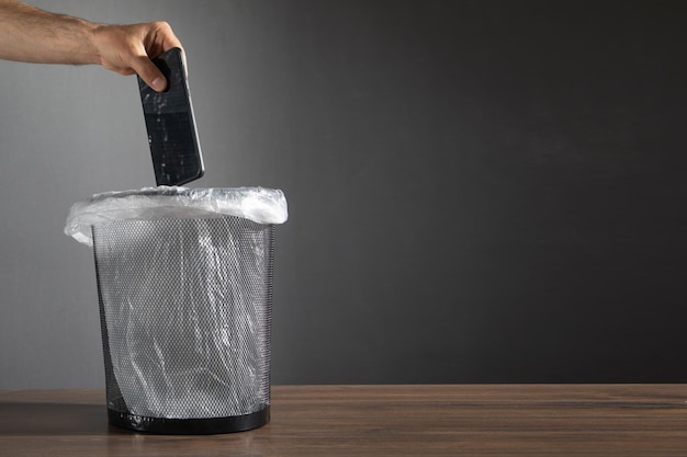 Male hand throws smartphone into the trash