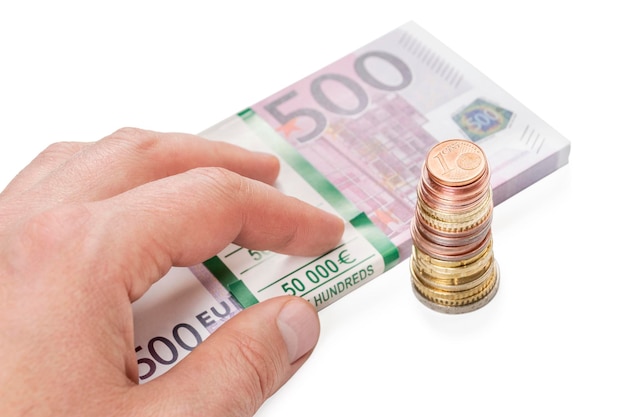 male hand on top of a bundle of paper euro money and a stack of coins isolated on white background