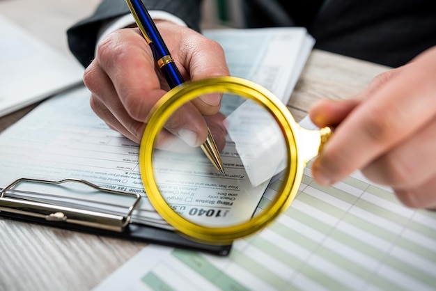 Photo male hand using magnifying glass and work with 1040 tax form