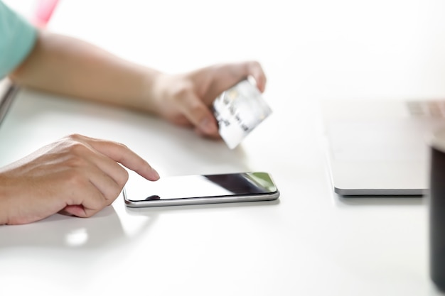 Male hand using mobile smart phone with credit card for payment or banking online.