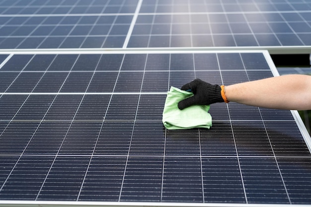 Male hand with cloth cleaning solar panel concept of photovoltaic module maintenance