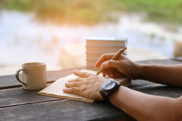 Male hand writing some data in notebook on the desk